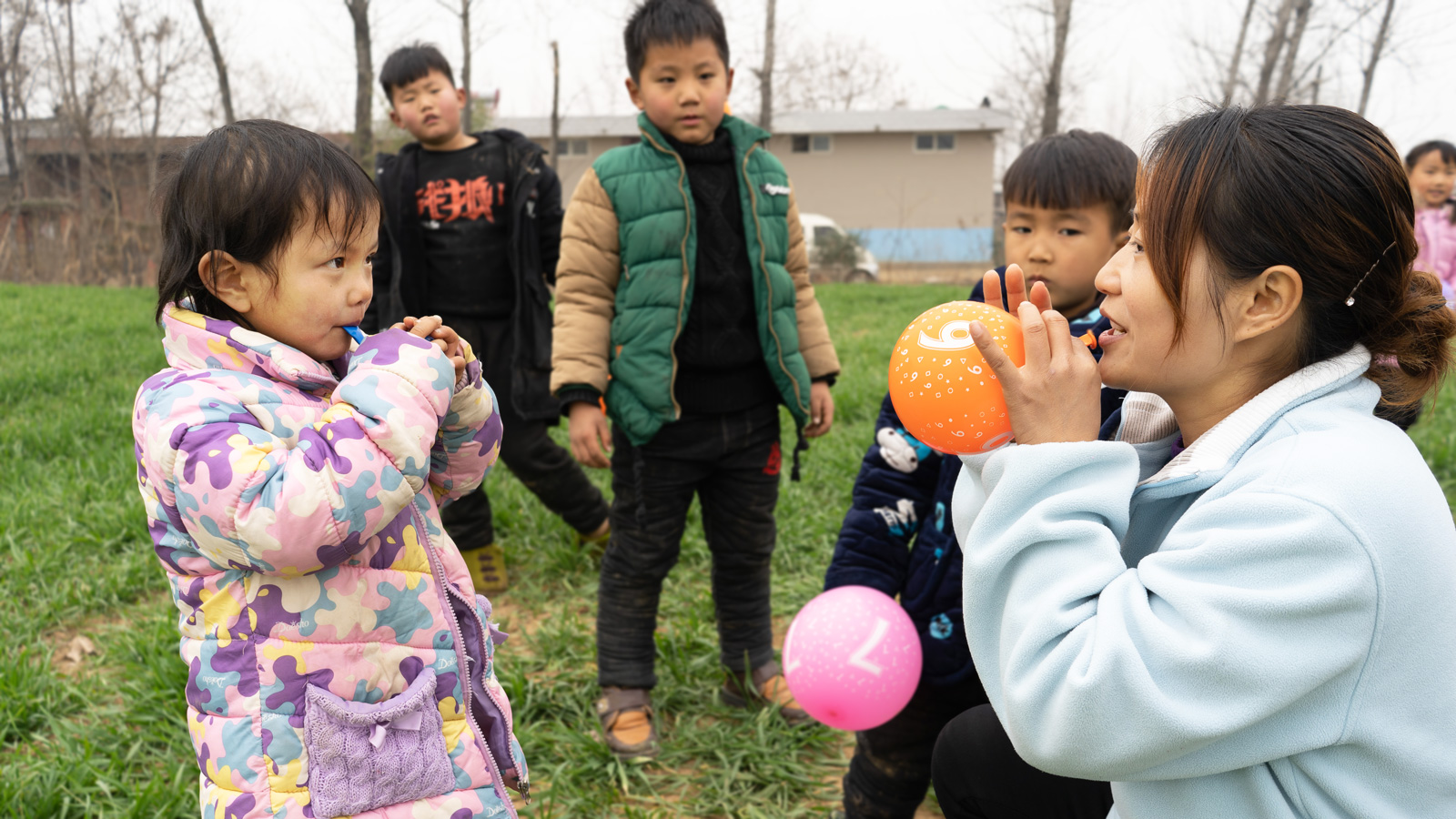 Zhenzhen blows a balloon with her teacher